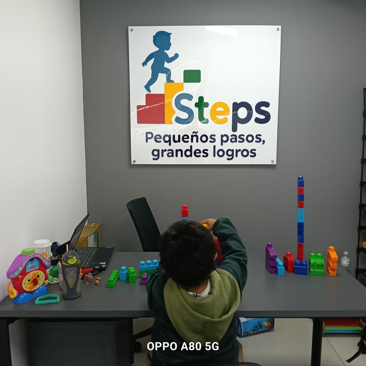 Consultorio de Steps con el logo en la pared y un niño jugando con bloques